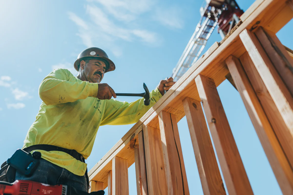 A contractor in a hard hat framing a wall
