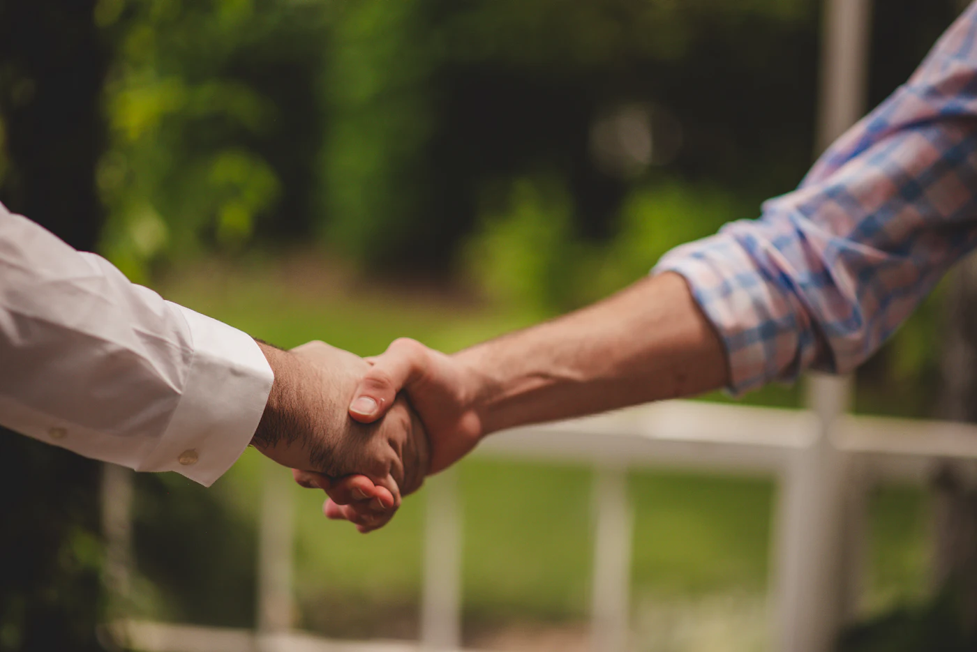 A homeowner shaking hands with a tradesperson in the garden