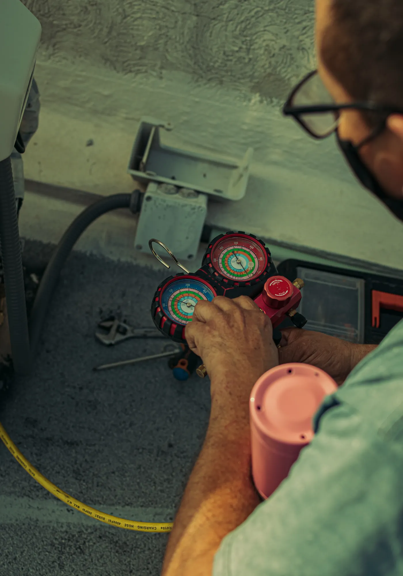A technician reading refrigerant gauges during an AC tune-up