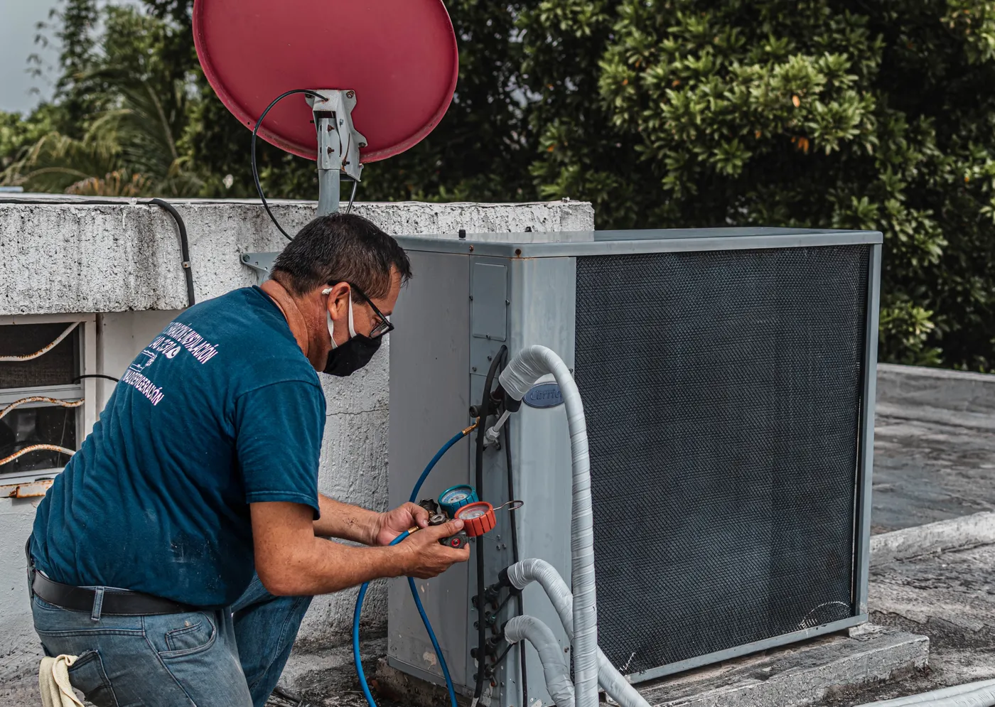 An HVAC technician checking an air conditioner with a manifold gauge