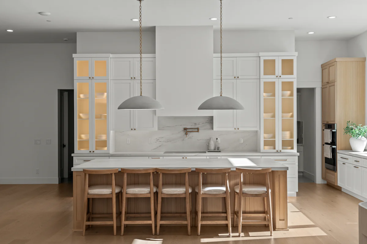A finished white kitchen remodel with an island and bar stools