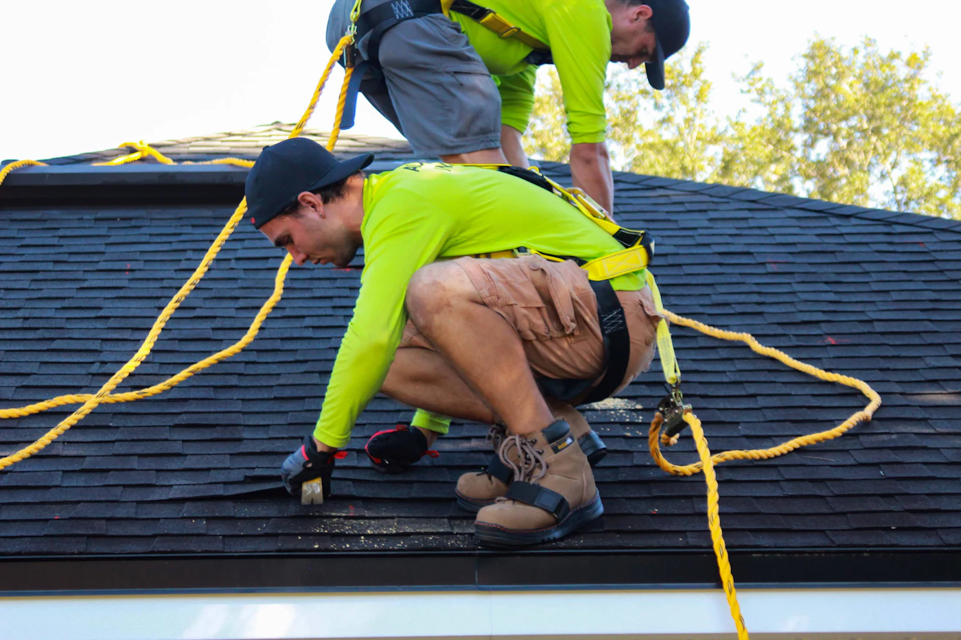 Two roofers laying shingles on a house roof