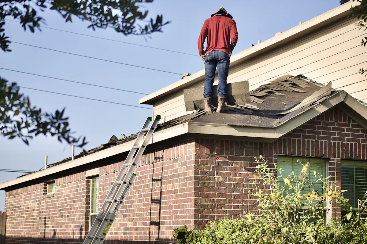 A roofer standing on a ranch house roof next to his ladder