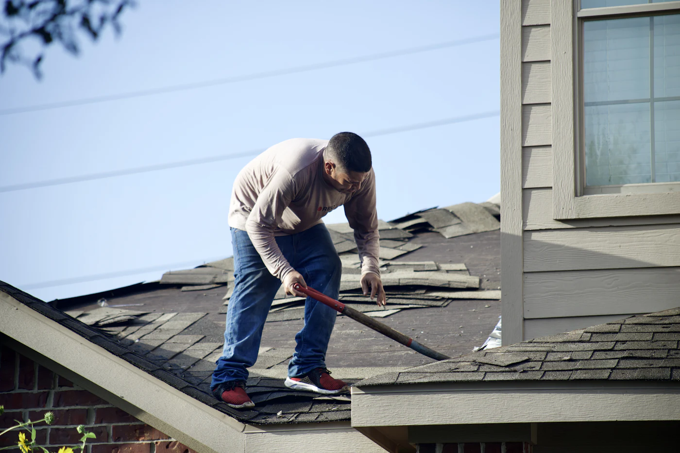 A roofer tearing off old shingles